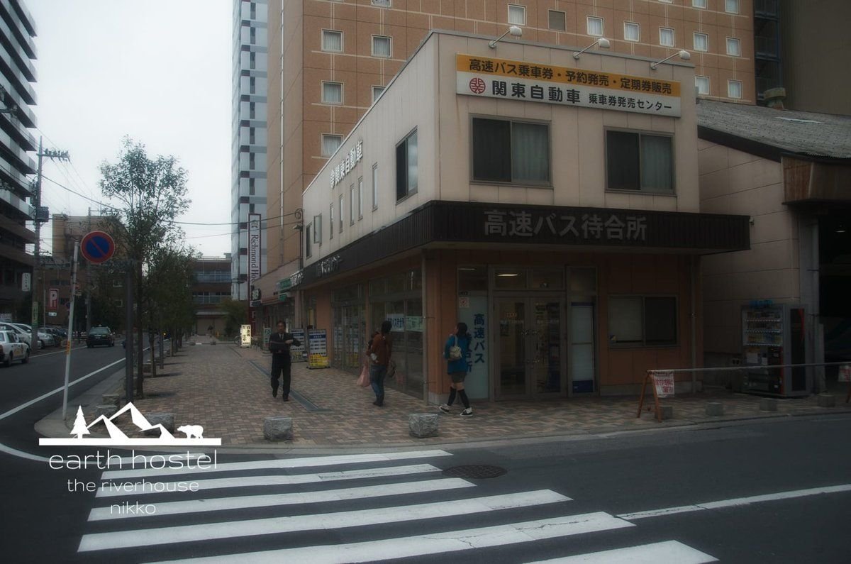 A building on the corner of a street adjacent to Narita Nikko Airport Bus.