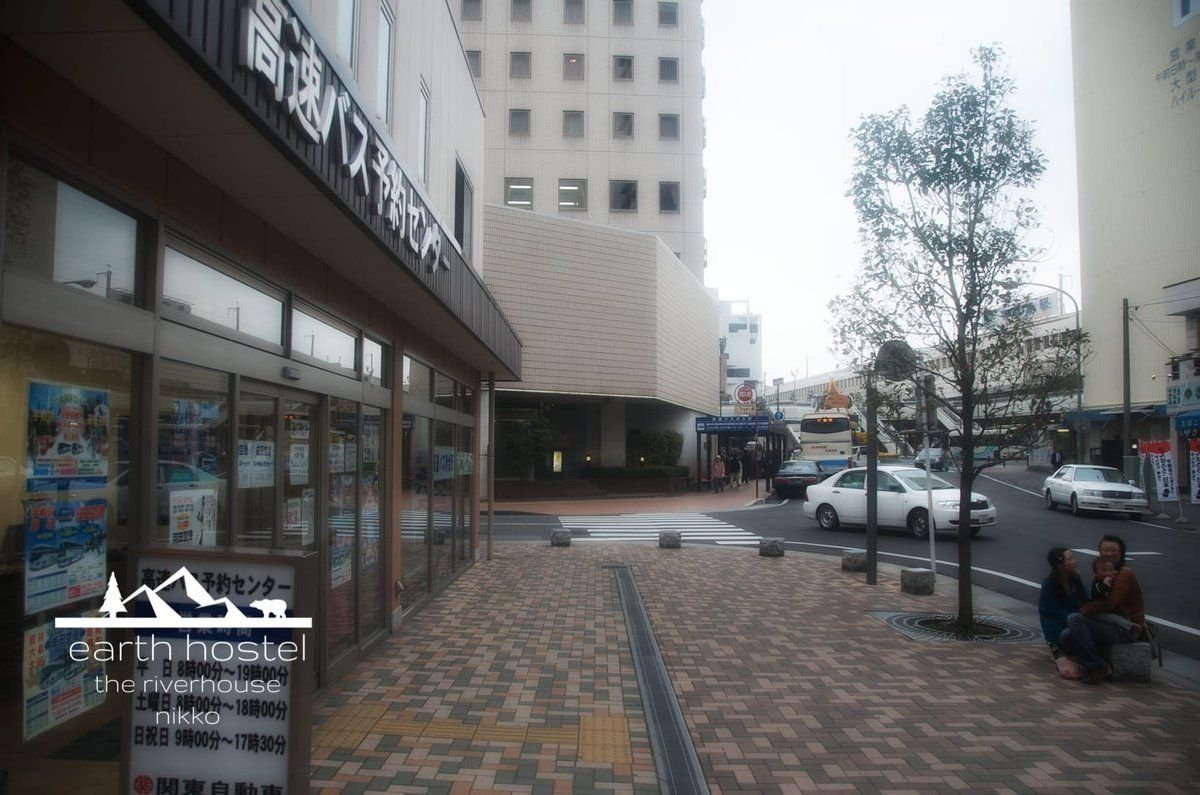 A person is sitting on a sidewalk in front of a building near Narita Airport.