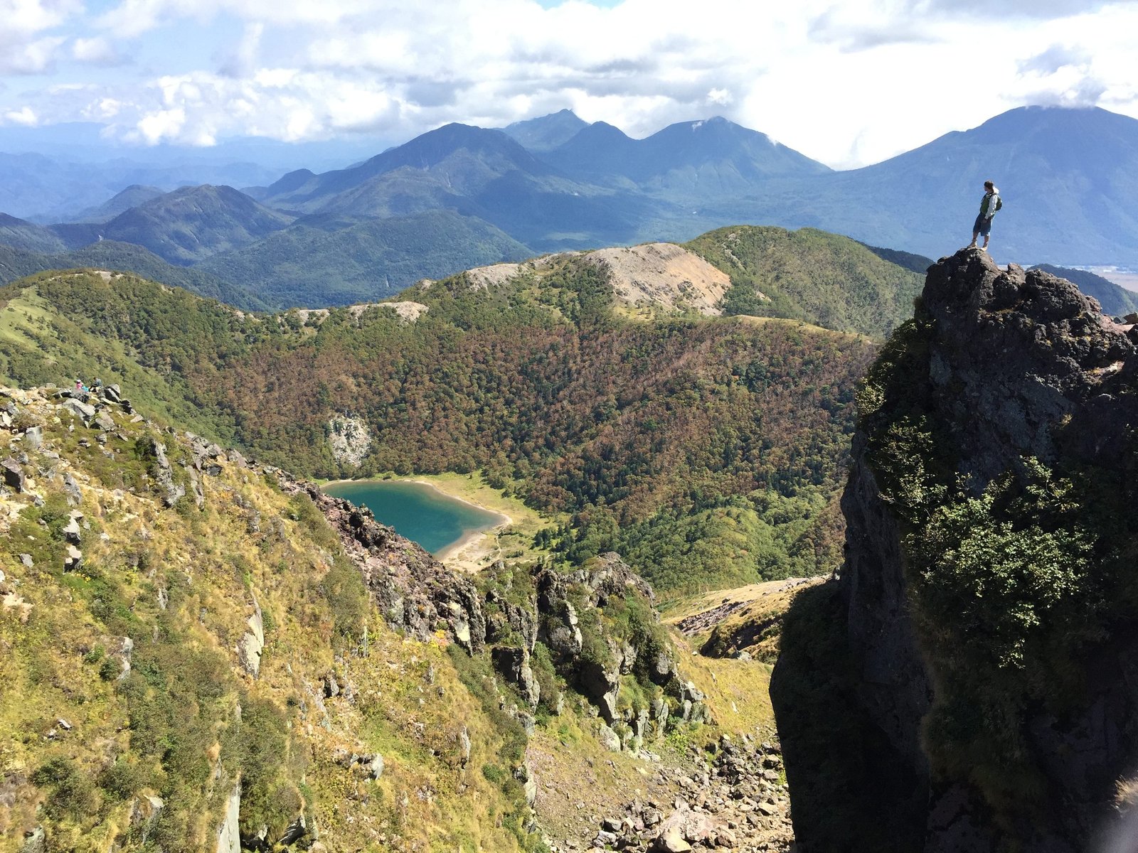 Hiker standing on a rock at the summit of Mount Nikko-Shirane, Nikko Japan